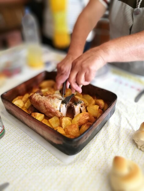 cropped hands cutting food in container on table