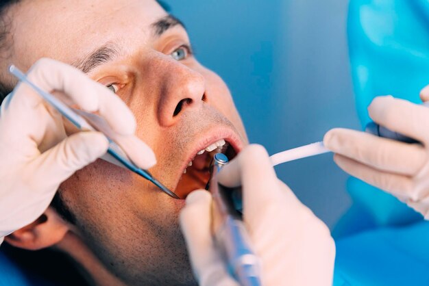 Photo cropped hands of dentists examining man in clinic