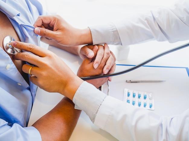 Photo cropped hands of doctor examining patient with stethoscope