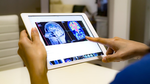 Foto mani tagliate di un medico che tiene una tavoletta digitale con una radiografia sul tavolo