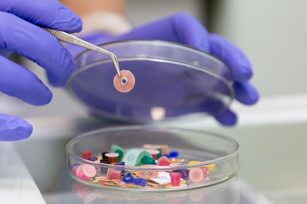 Cropped hands of doctor holding medical equipment in glass container on table