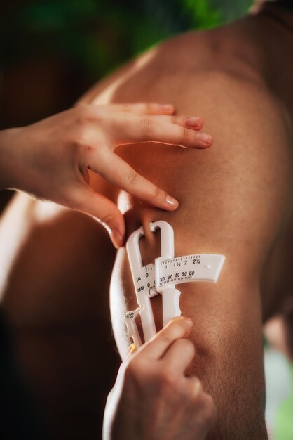 Cropped hands of doctor measuring patient fat in hospital