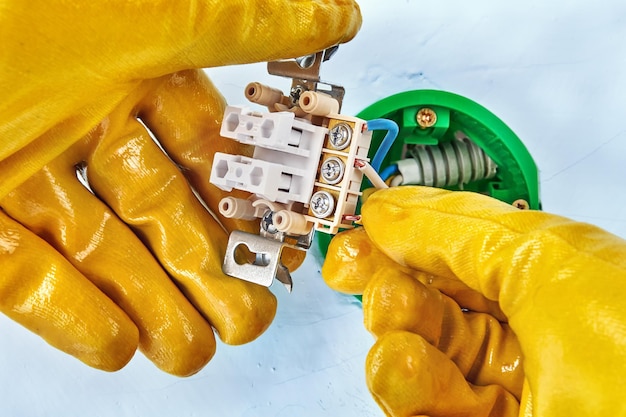 Cropped hands of electrician working over electric plug on wall