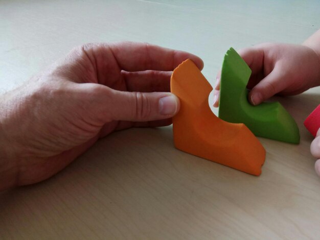 家のテーブルの上でおもちゃで遊んでいる父親と子供の切断された手