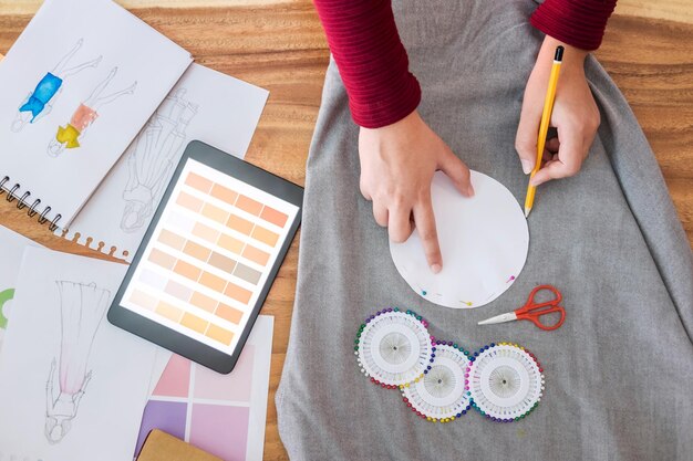 Foto mani tagliate di una stilista di moda che segna sul tessuto alla scrivania