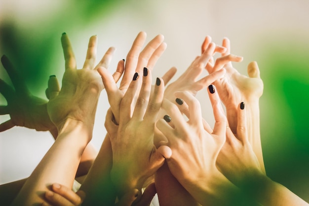 Photo cropped hands of female friends with arms raised against wall