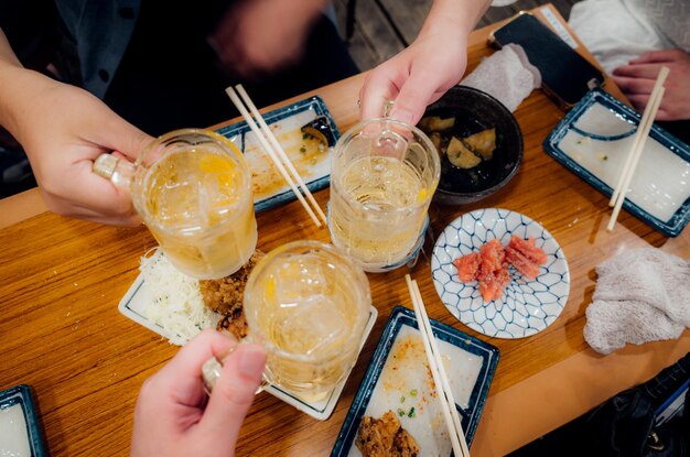 Cropped hands of friends toasting beer glasses at table in restaurant