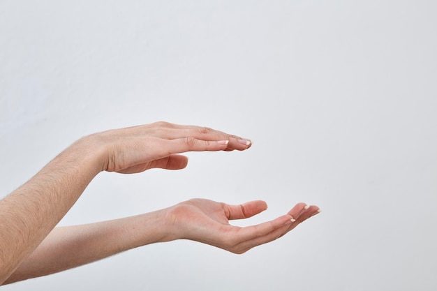 Photo cropped hands gesturing against white wall