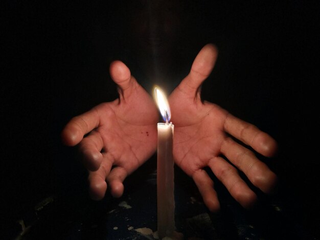 사진 어두운 방에서 불타는 불에 의해 몸짓을 하는 잘라진 손