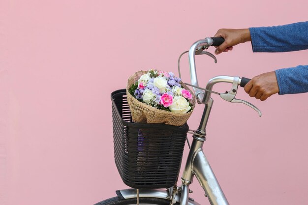 Cropped hands holding bicycle handle against pink background