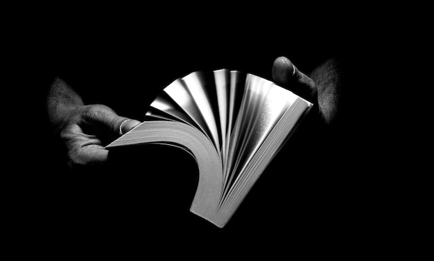 Foto mani tagliate che tengono un libro su uno sfondo nero