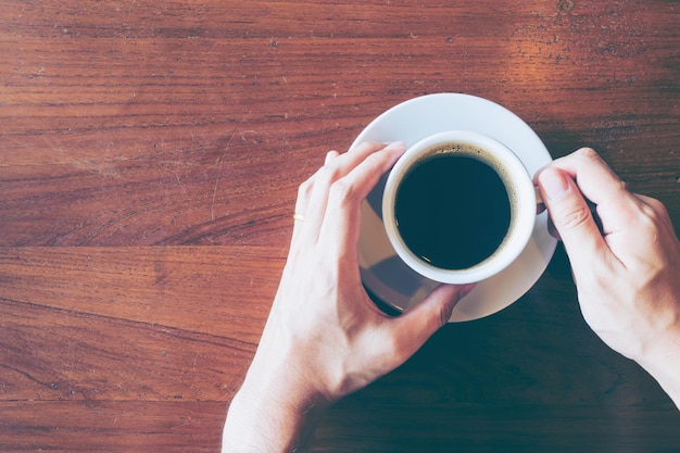 Photo cropped hands holding coffee cup on table