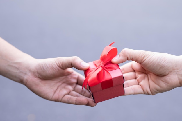 cropped hands holding gift box against gray background