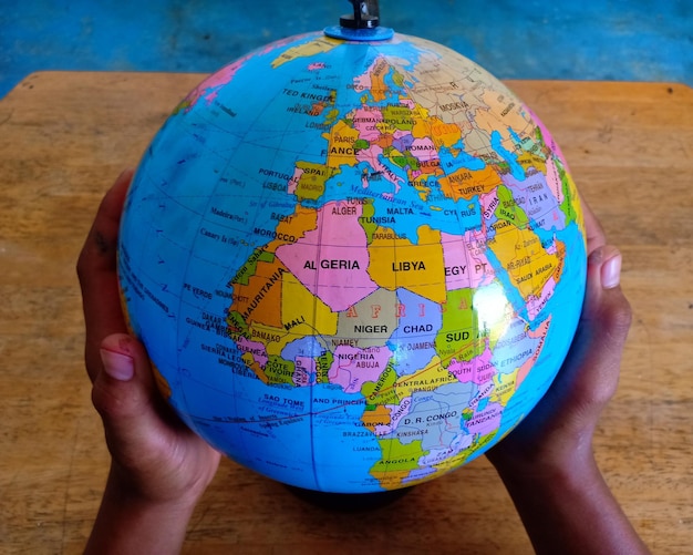 Cropped hands holding globe over table