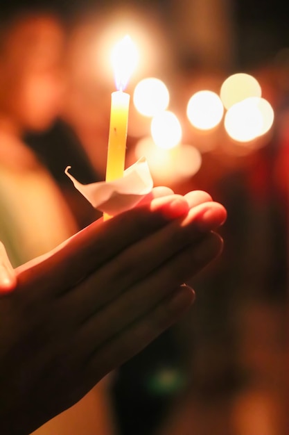 Mani tagliate che tengono una candela illuminata di notte