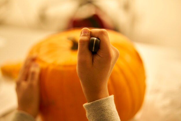 Photo cropped hands holding knife and pumpkin on table during halloween