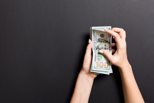 Photo cropped hands holding paper currencies on gray background