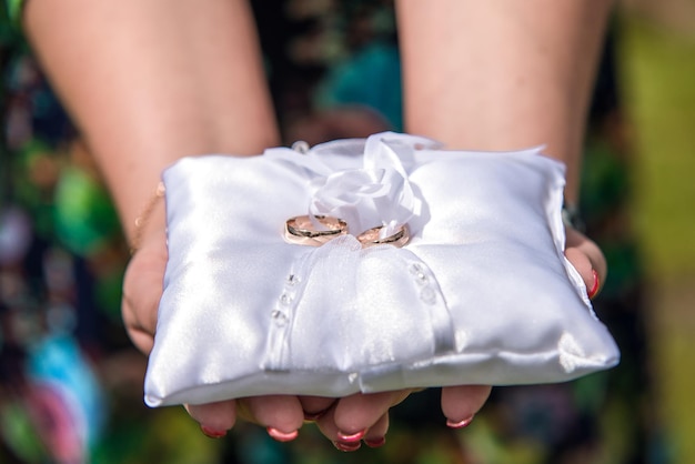 Photo cropped hands holding wedding rings on cushion