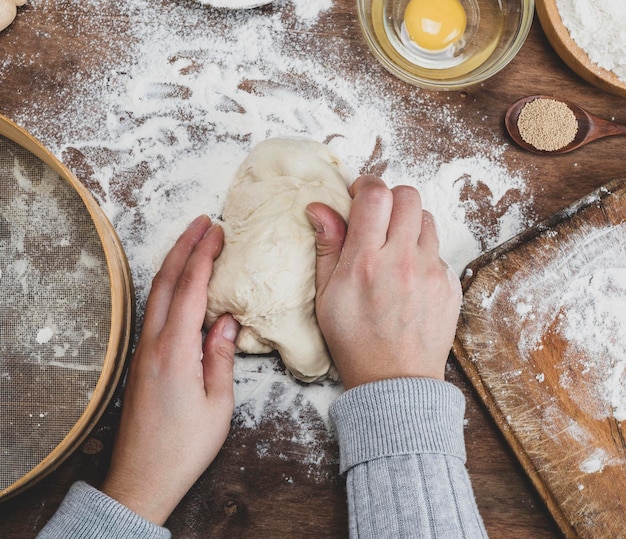 Cropped hands kneading dough on table