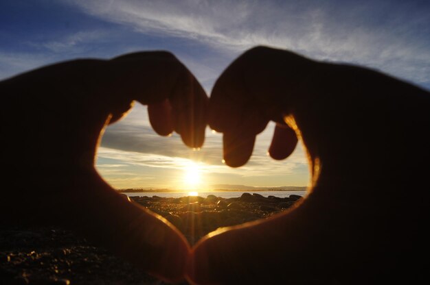 写真 太陽に逆らってハートの形をした手を切り取った