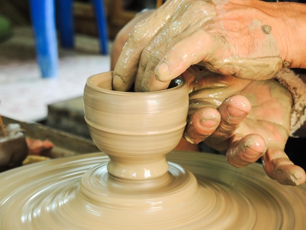 cropped hands making pot on pottery wheel