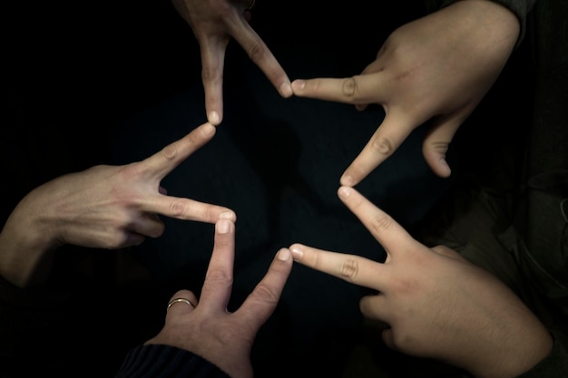 Photo cropped hands making star shape against black background