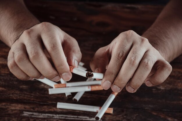 Photo cropped hands of man breaking cigarette on table