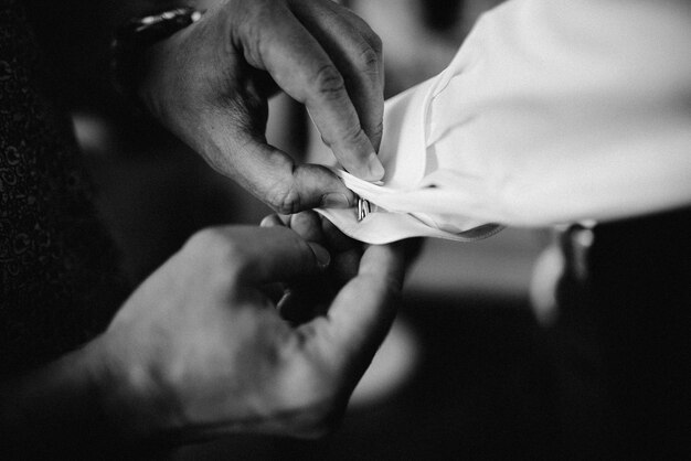 Photo cropped hands of man buttoning friend cuffs