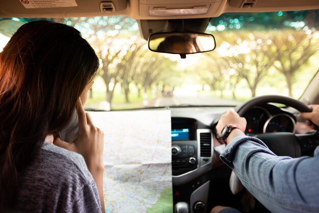 Foto mani tagliate di un uomo che guida un'auto mentre una donna legge una mappa