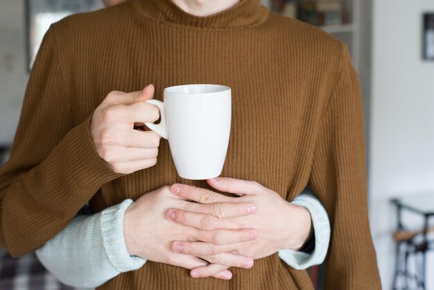 Photo cropped hands of man embracing boyfriend holding cup