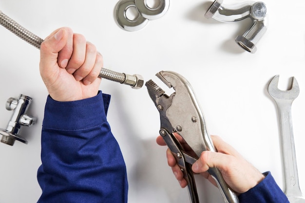 Photo cropped hands of man holding hand tools on white table