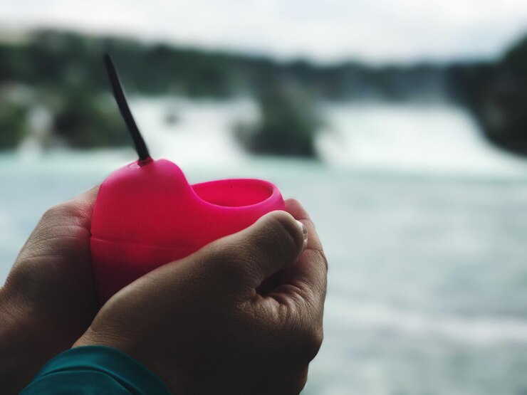 Photo cropped hands of man holding plastic bowl by river