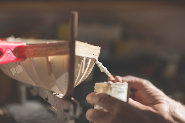 Cropped hands of man making wooden model boat at workshop