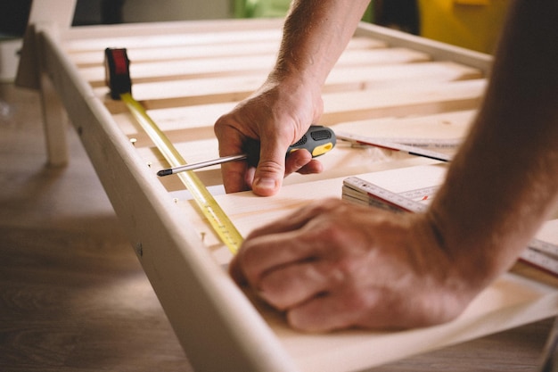 Foto mani tagliate di un uomo che misura il legno a casa
