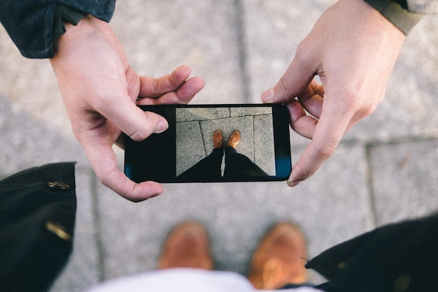 Cropped hands of man photographing person legs