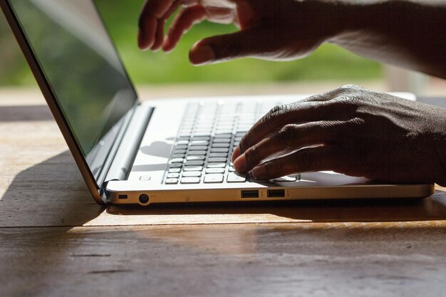 Photo cropped hands of man using laptop on table