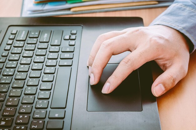 Photo cropped hands of man using laptop on table