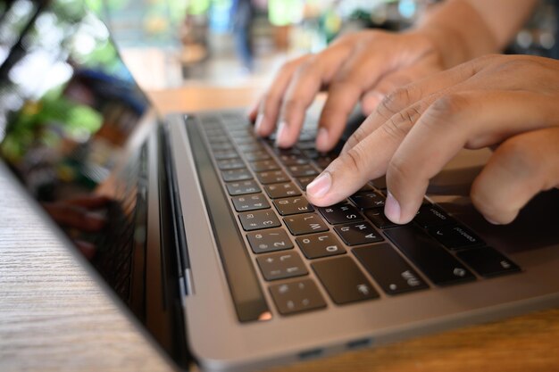 Cropped hands of man using laptop at table