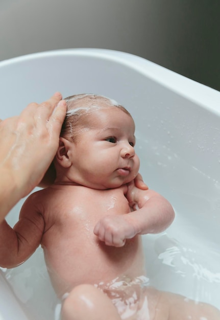 Photo cropped hands of mother bathing son in bathtub at bathroom