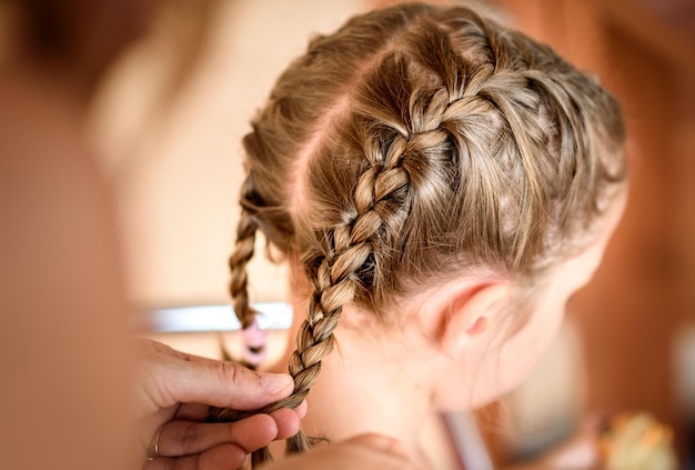 Photo cropped hands of mother braiding daughter hair