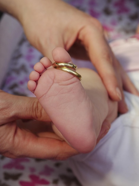cropped hands of mother holding baby feet while wearing rings