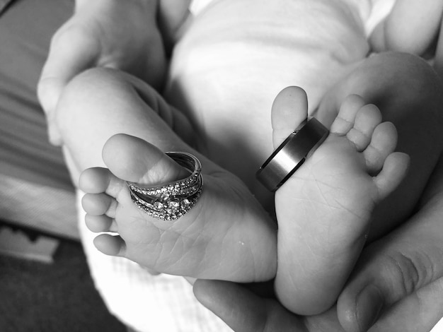 Photo cropped hands of parent holding baby feet with rings