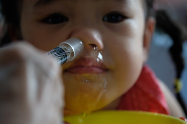Foto mani tagliate del genitore che inietta la medicina nel naso della figlia