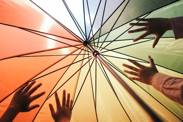 cropped hands of people against umbrella