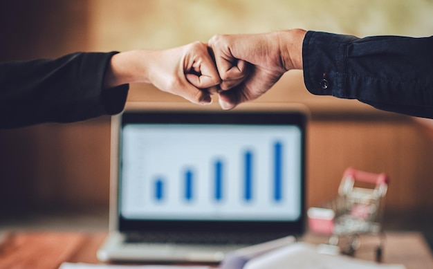 Cropped hands of people giving fist bump at office