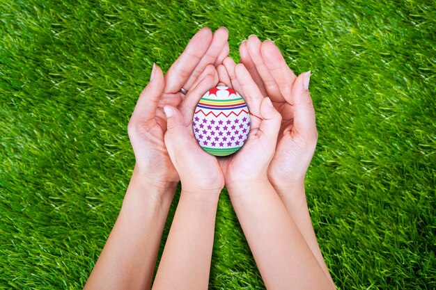 Photo cropped hands of people holding easter egg on lawn