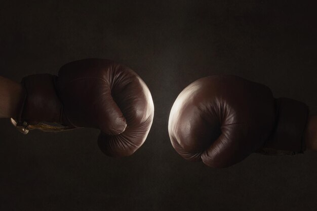 Photo cropped hands of people wearing boxing gloves against black background