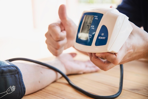 cropped hands of person checking blood pressure of patient with gauge at home