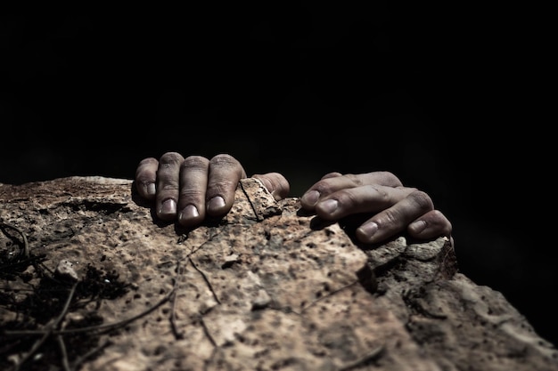 Cropped hands of person climbing rock at night