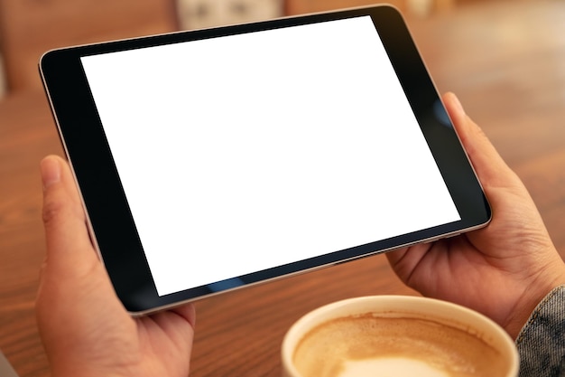 Foto mani tagliate di una persona che tiene un tablet digitale in un caffè